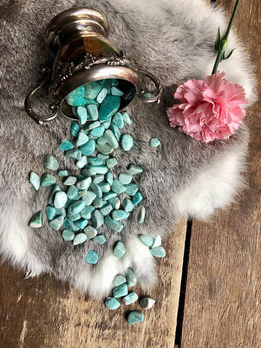 Amazonite Crystals lay spilled out on top of fur and antique wood, framed by spring flowers