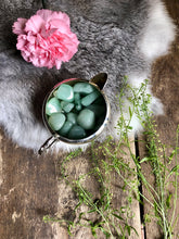 Load image into Gallery viewer, Aventurine tumbles sit in silver dish on top of fur and antique wood framed with greenery and pink flower
